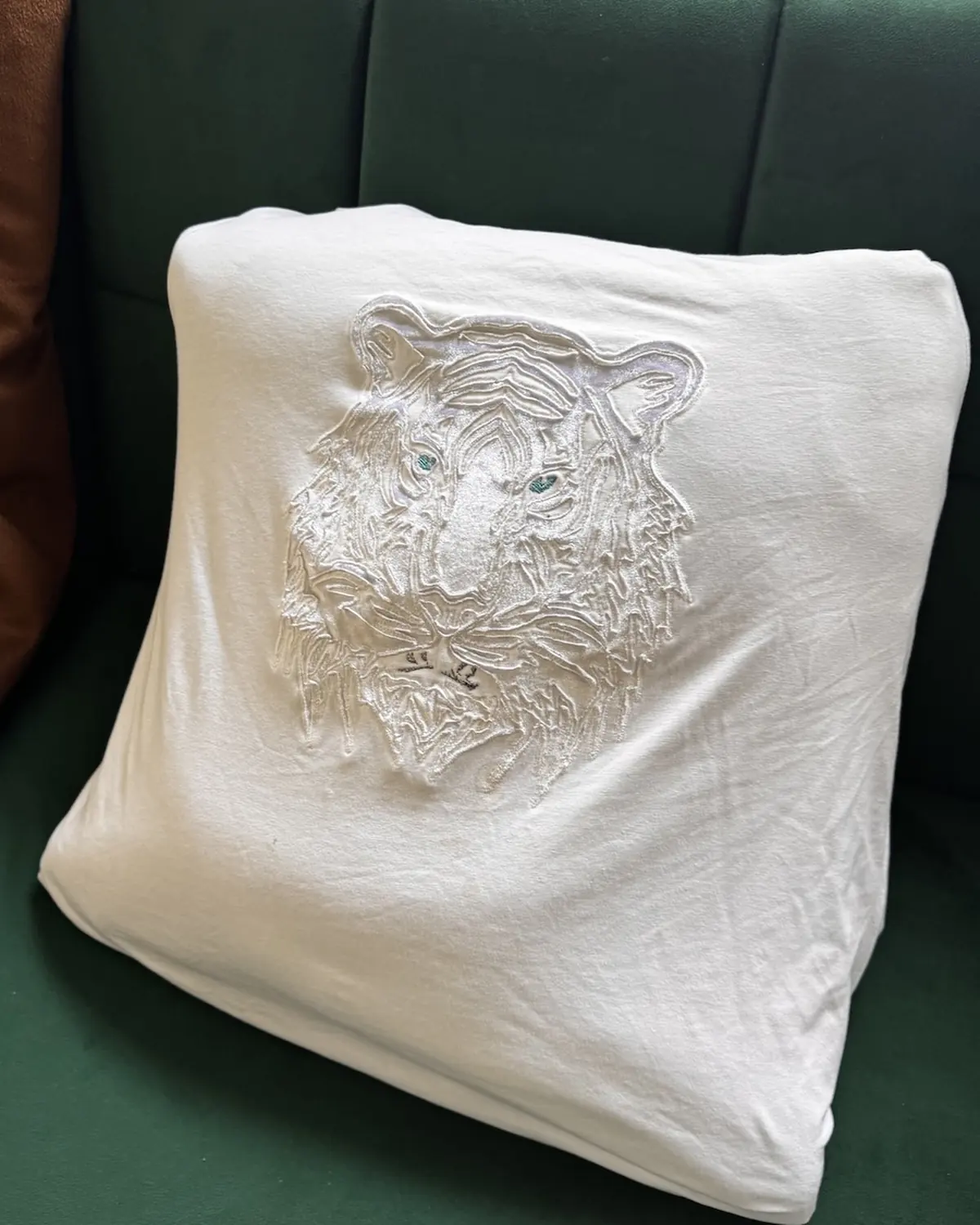 White satin Monolit Tiger pillow cover, the tiger motif machine-embroidered into the fabric and held by tensioned thread.